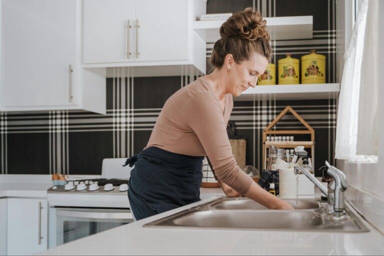 A woman cleaning dishes in her sink.